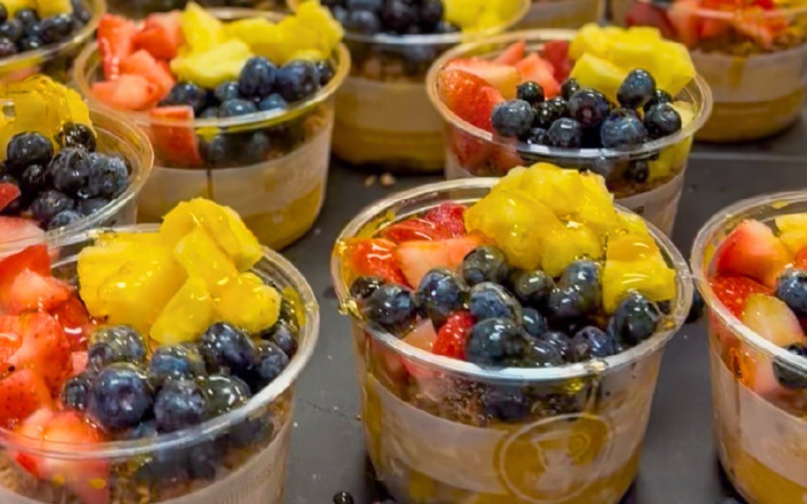 Acai bowls with fresh blueberries, strawberries, mango, and granola in clear plastic cups at Better Blend Brandon